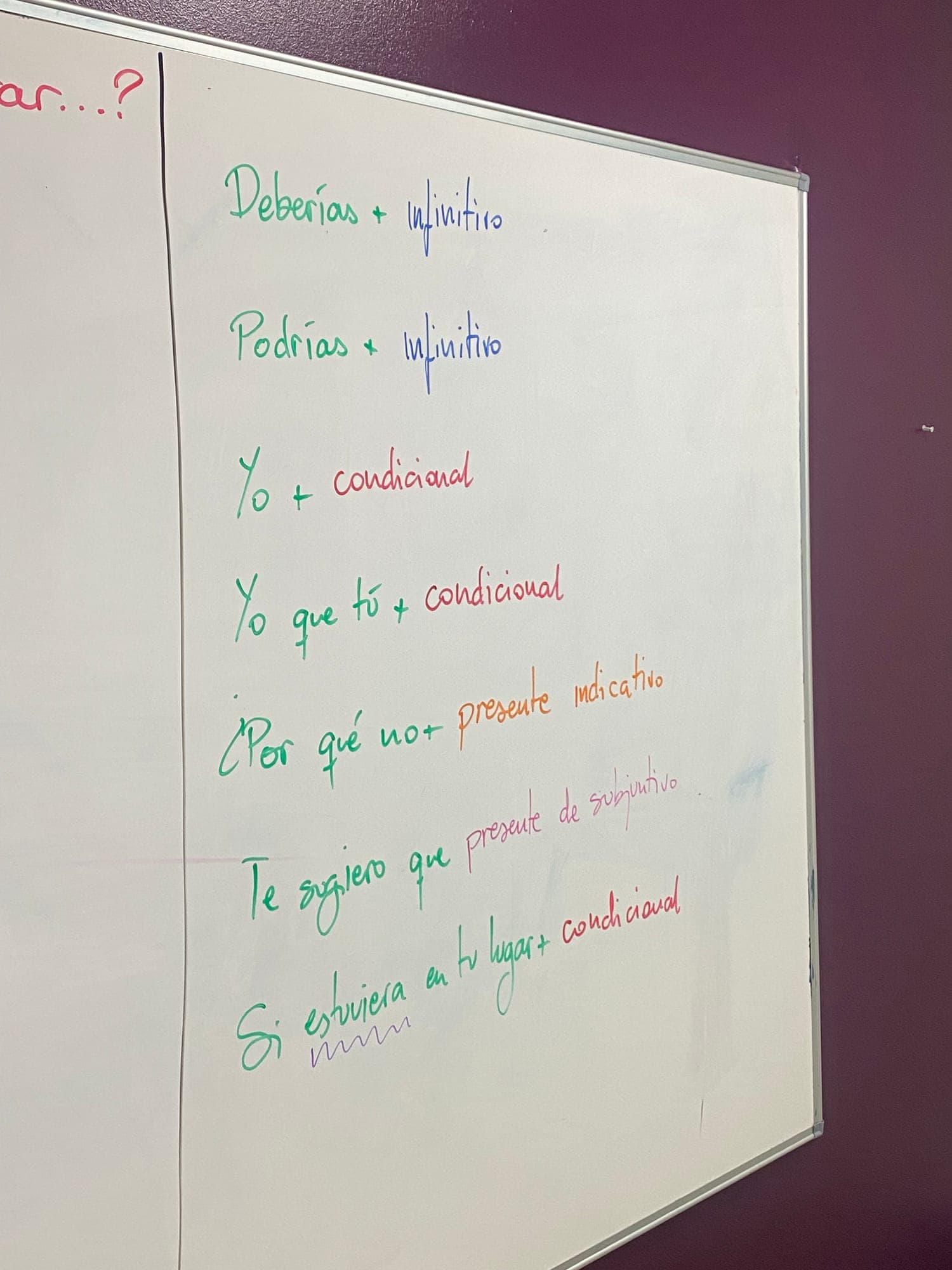 A whiteboard covered in handwritten Spanish grammar notes from a lesson.